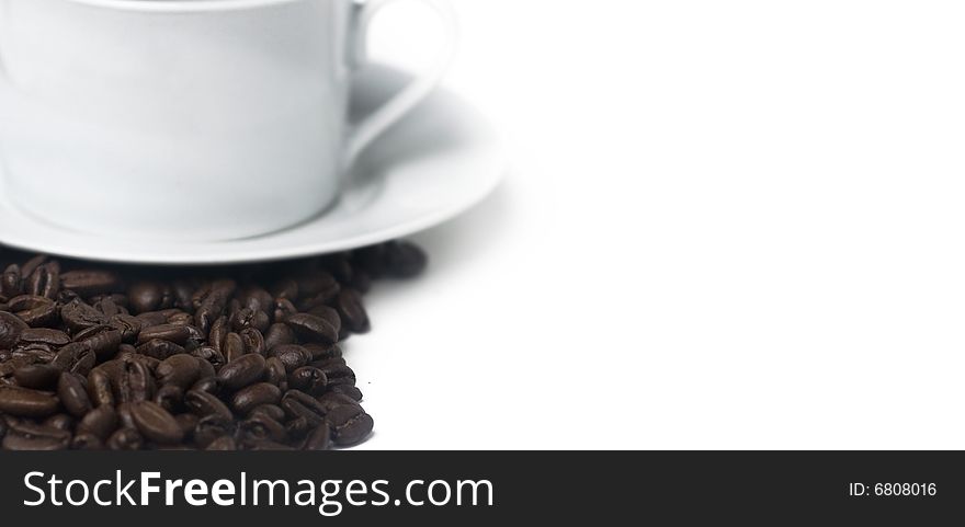 Coffee beans and cup and saucer framing left side of picture with copy space.