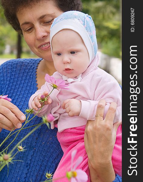 The child on hands at mum looks at a flower