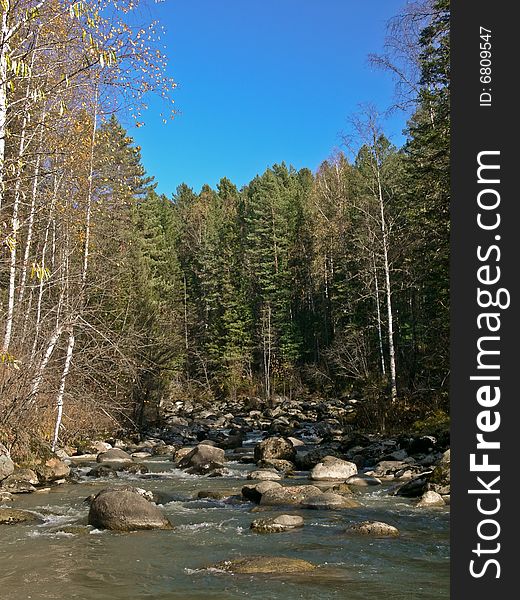 Autumn on the river Yurtok. Stones in water flow.