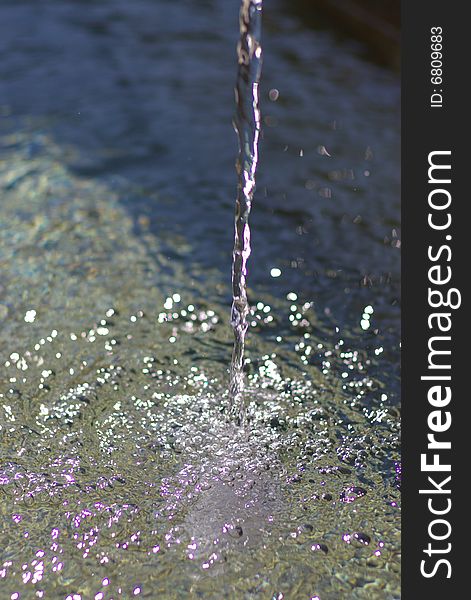 Dropping potable stream of water in sunlight, vertical. Dropping potable stream of water in sunlight, vertical