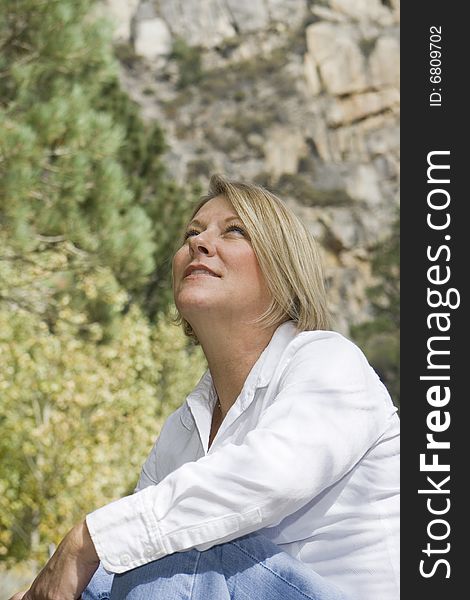 Healthy mature woman in an outdoor setting looking up at the sky. Healthy mature woman in an outdoor setting looking up at the sky.