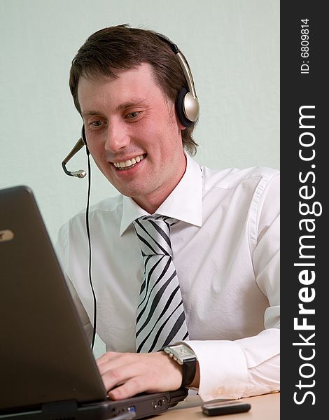 The young businessman speaks by phone and works on a computer