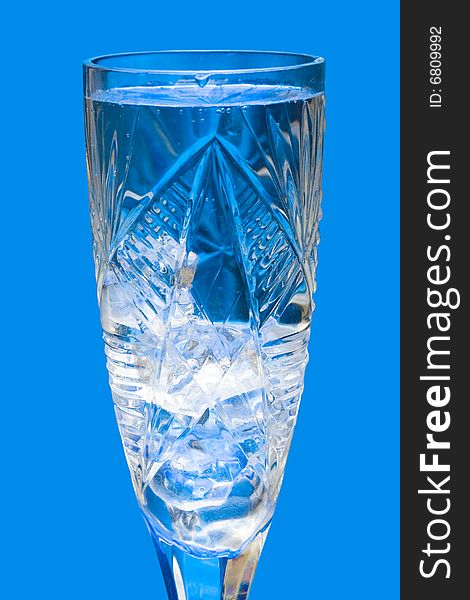 Glass with water and ice over blue