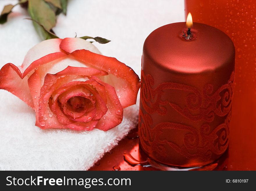 Candle with rose and towel on red background