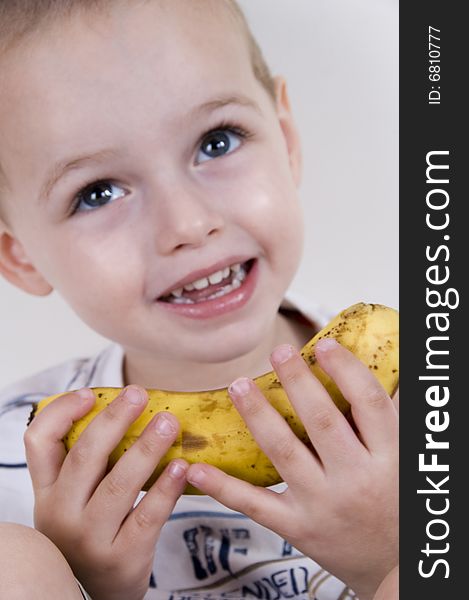 Close up of little boy smiling and holding a banana
