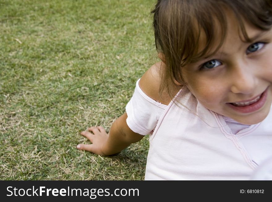 Smiling Little Girl Sitting On Grass