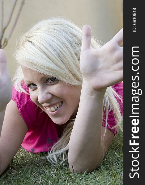 Young woman lying on green grass showing her palm