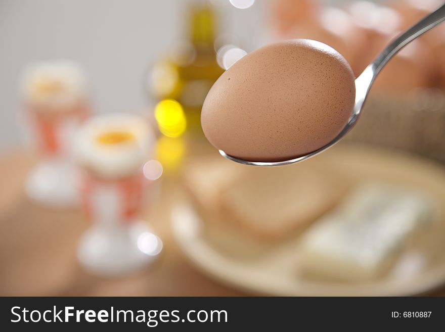 Breakfast table with toast bread and boiled eggs in cups in blur with windows reflections in the background. Breakfast table with toast bread and boiled eggs in cups in blur with windows reflections in the background.