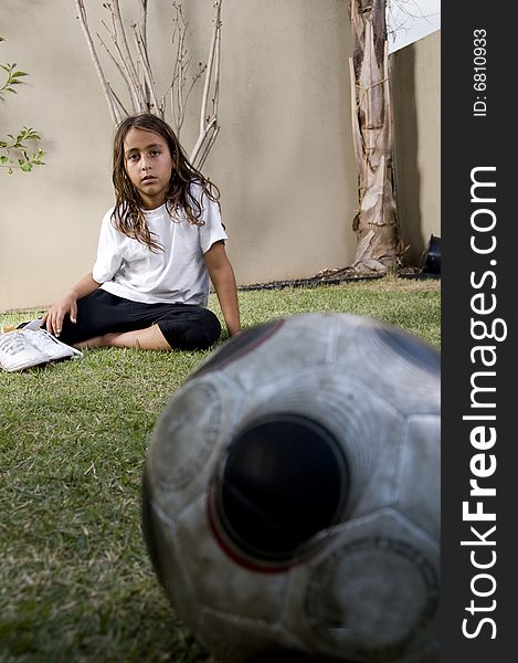 Tired boy sitting on lawn near soccer ball. Tired boy sitting on lawn near soccer ball