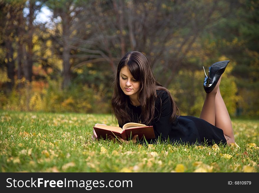 Young girl reading a book on the meadow