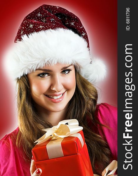 Winter portrait of a beautiful young smiling woman with a christmas cap and a gift. Winter portrait of a beautiful young smiling woman with a christmas cap and a gift