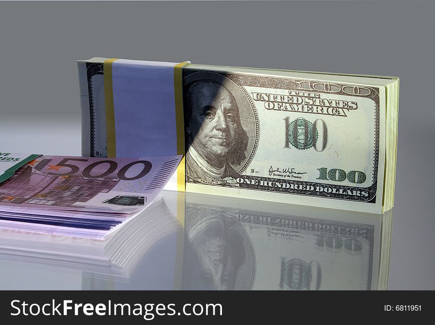 Two packs of dollars and euro bank notes on gray background. Two packs of dollars and euro bank notes on gray background