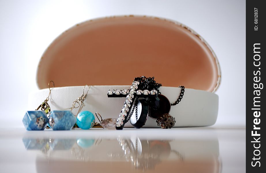 An open jewelry box with the jewels spilling out and the reflection of the box in front.