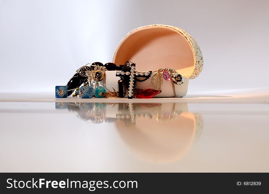 An open jewelry box with the jewels spilling out and the reflection of the box in front.