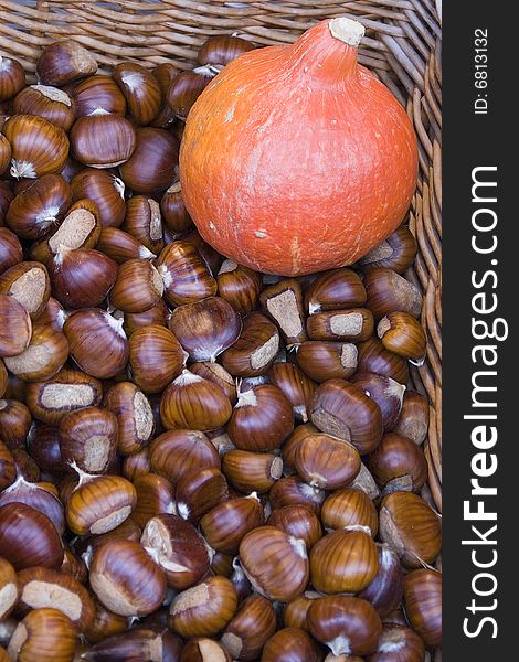 Basket full of sweet chestnut with an orange squash. (autumn in a French Riviera market). Basket full of sweet chestnut with an orange squash. (autumn in a French Riviera market)