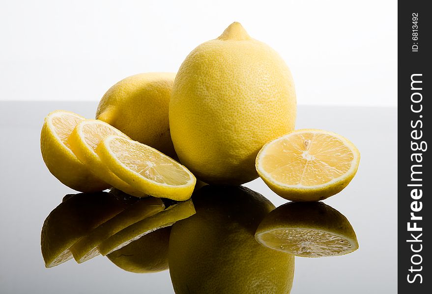Sliced and whole yellow lemons on mirrored background. Sliced and whole yellow lemons on mirrored background