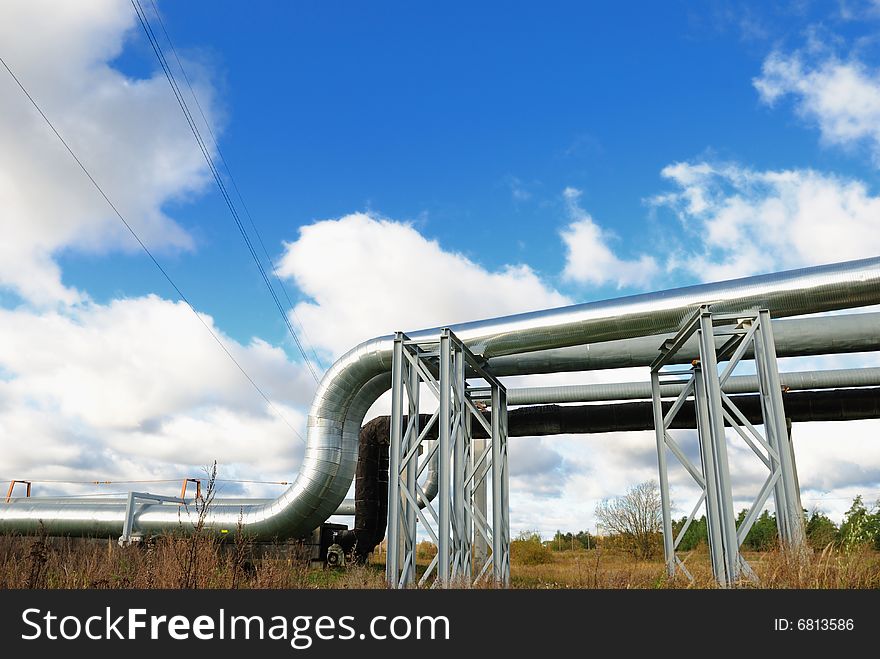 Industrial pipelines on pipe-bridge against blue sky.