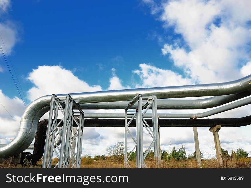 Industrial pipelines on pipe-bridge against blue sky.