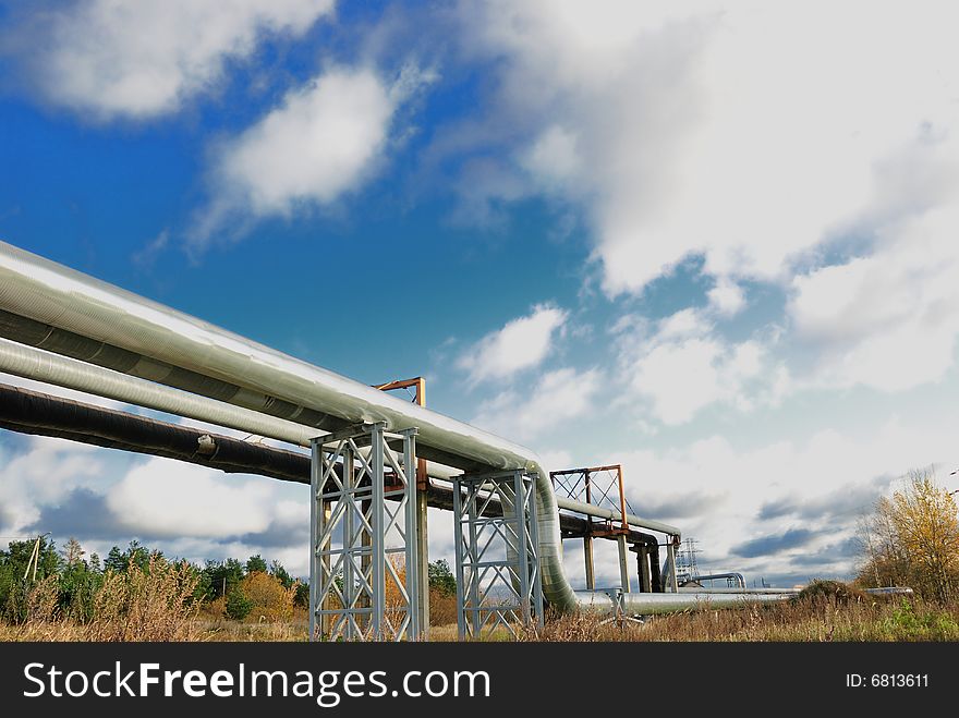 Industrial pipelines on pipe-bridge against blue sky.