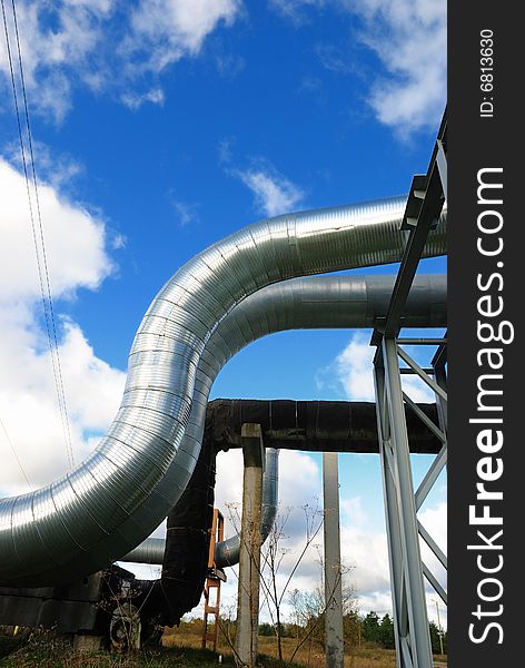 Industrial pipelines on pipe-bridge against blue sky.