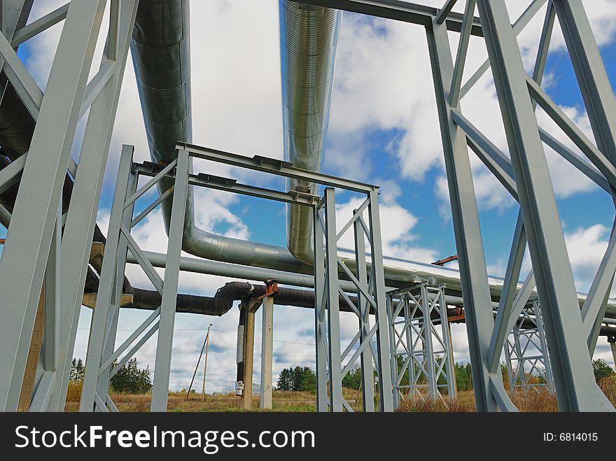 Industrial pipelines on pipe-bridge against blue sky.