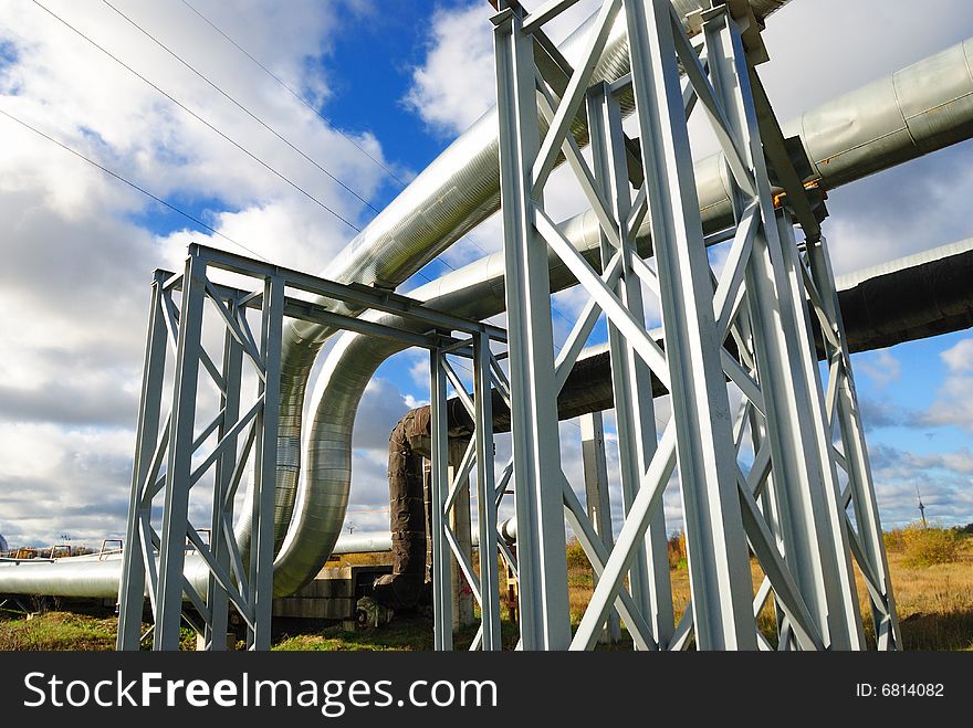 Industrial pipelines on pipe-bridge against blue sky.