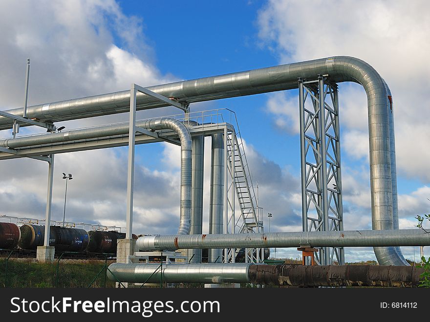 Industrial pipelines on pipe-bridge against blue sky.