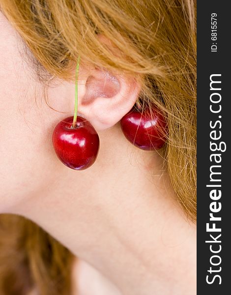 Woman ear with cherry earrings