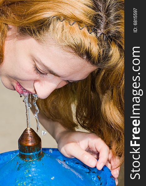 Woman drinking water from a street tap