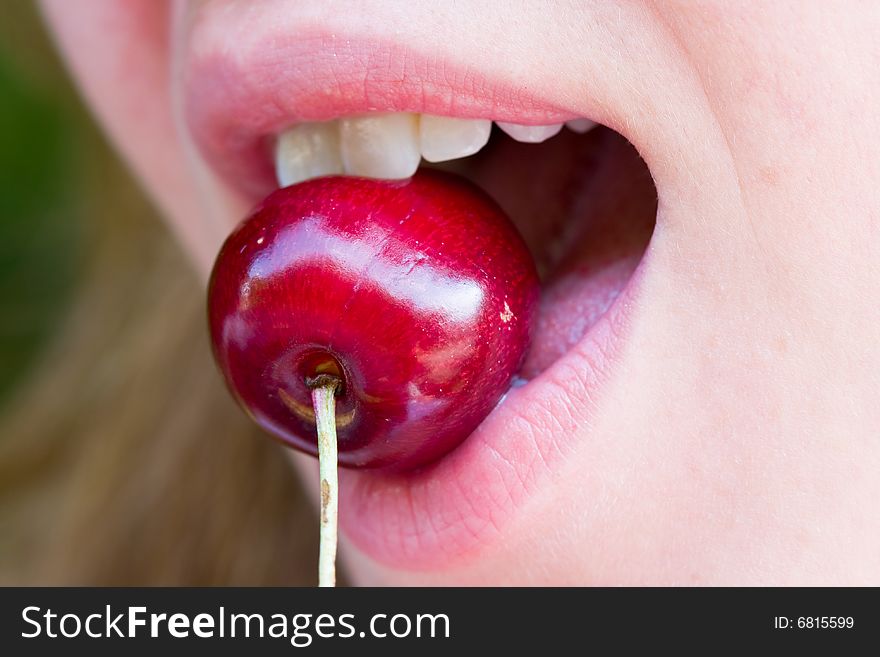 Closeup of a woman biting a red cherry