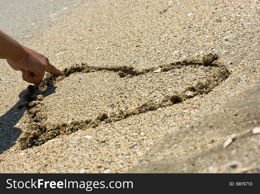 Drawing a heart in wet sand