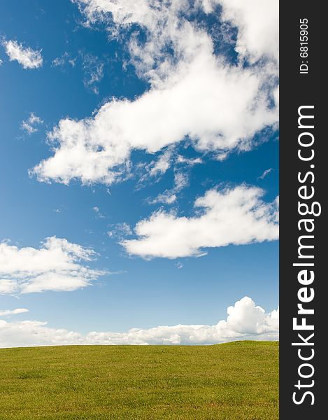 Green meadow and the blue sky with white clouds
