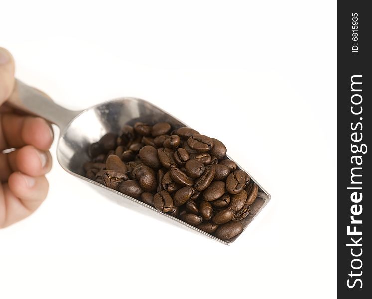 Coffee beans falling from silver shovel set against white background