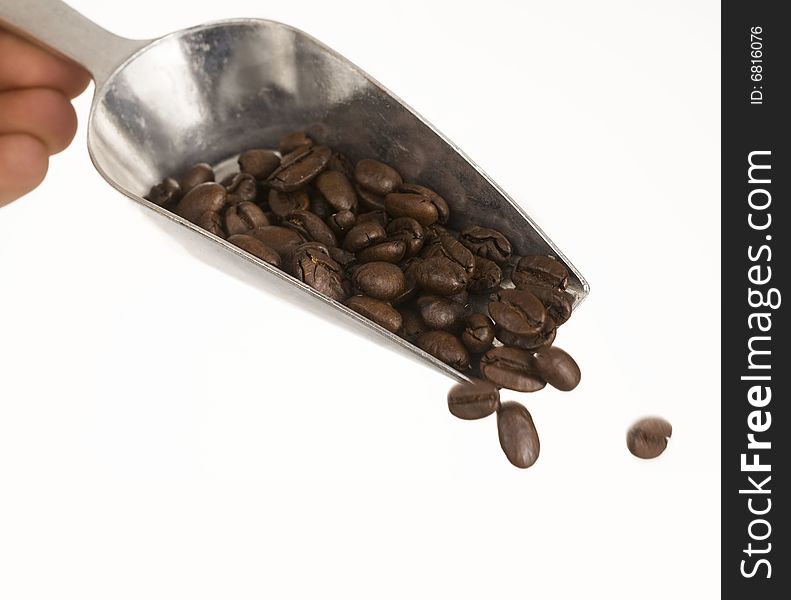 Coffee beans falling from silver shovel set against white background