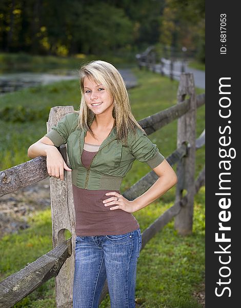 Beautiful young teenage girl leaning on a fence. Beautiful young teenage girl leaning on a fence