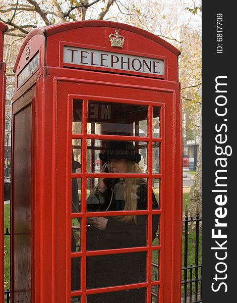 Blonde woman talking on the phone in a London Call Box. Blonde woman talking on the phone in a London Call Box