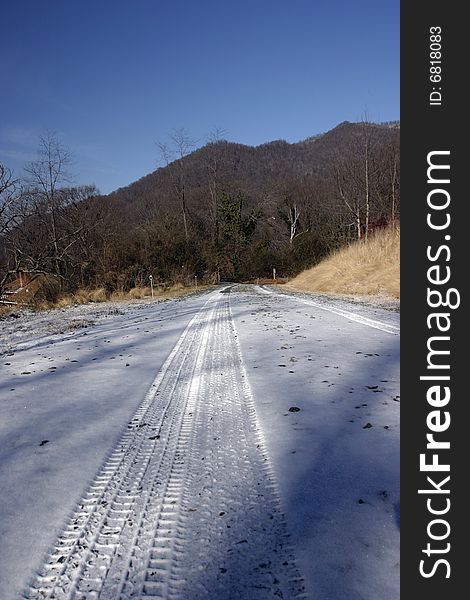 Tire tracks in the snow on a road near mountains. Tire tracks in the snow on a road near mountains