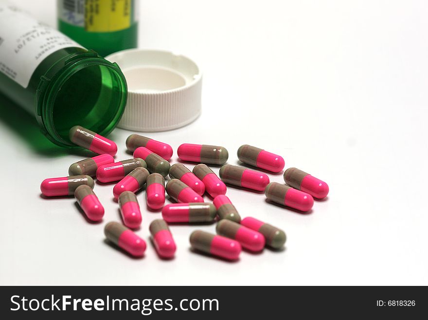 Pink and brown pills spilled from green bottle. Pink and brown pills spilled from green bottle