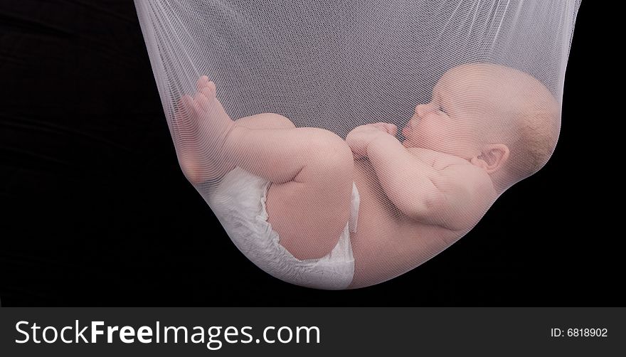 Little baby held in the net over black background