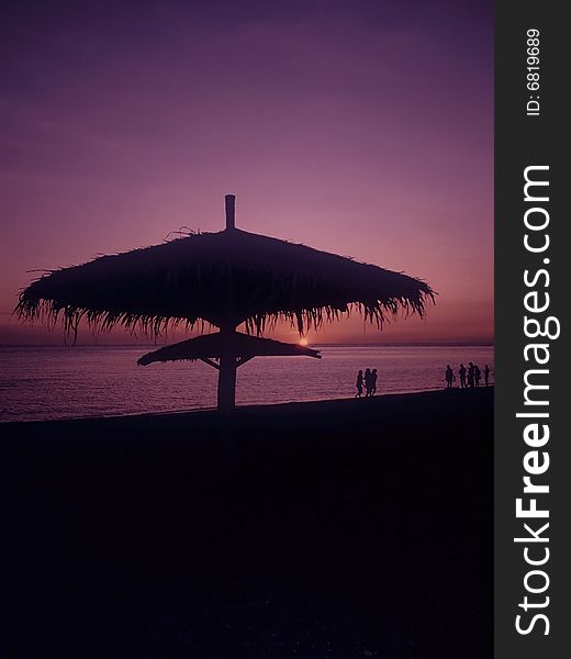 People is strolling along the shore at a beach resort as sun down.