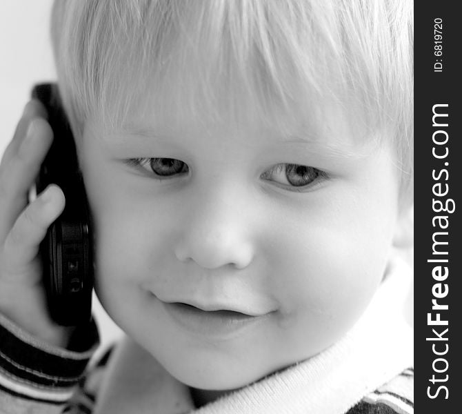 The child smiles and speaks on the phone. The child smiles and speaks on the phone