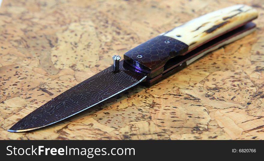 Stainless steel pocket knife isolated on the wood background