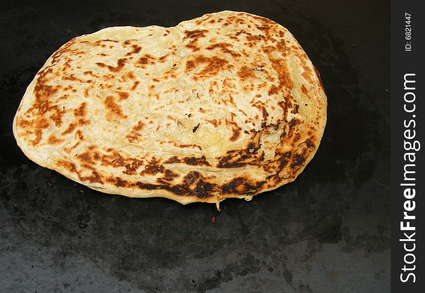 A freshly baked Italian flat bread on dark background. A freshly baked Italian flat bread on dark background