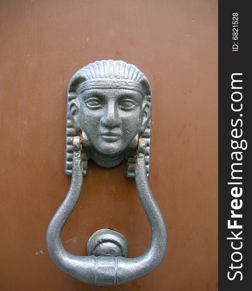 A silver door knocker in Egyptian style on brown background. A silver door knocker in Egyptian style on brown background