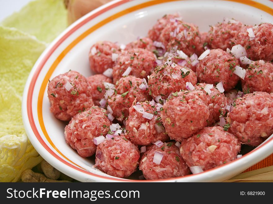 Some meat balls in a bowl with onions and coriander