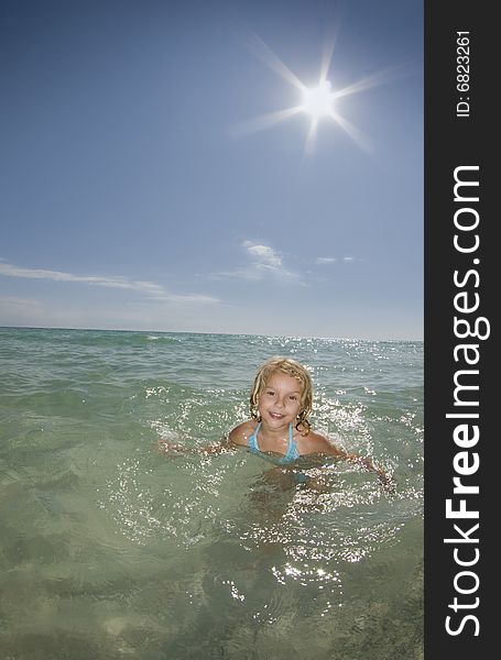 A young girl plays in the ocean on a calm bright sunny day. A young girl plays in the ocean on a calm bright sunny day