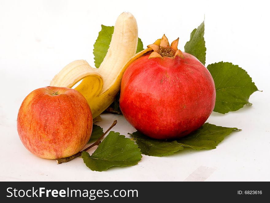 Pomegranate, apple, and banana on leaves. Pomegranate, apple, and banana on leaves