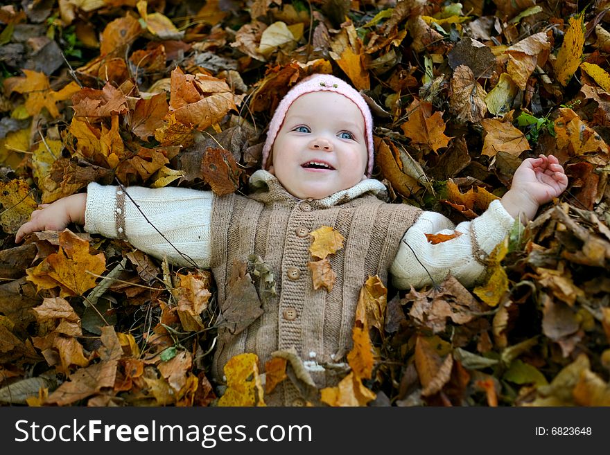 An image of nice child in leaves in autumn park. An image of nice child in leaves in autumn park