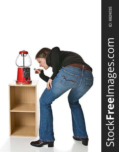 Confused or angry young woman in blue jeans tries to put a quarter into an empty gumball machine. Confused or angry young woman in blue jeans tries to put a quarter into an empty gumball machine.