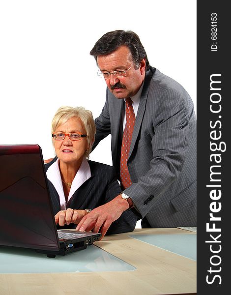 A business woman and a man in front of a laptop on a desk. The man explains something to the woman. Isolated over white. A business woman and a man in front of a laptop on a desk. The man explains something to the woman. Isolated over white.